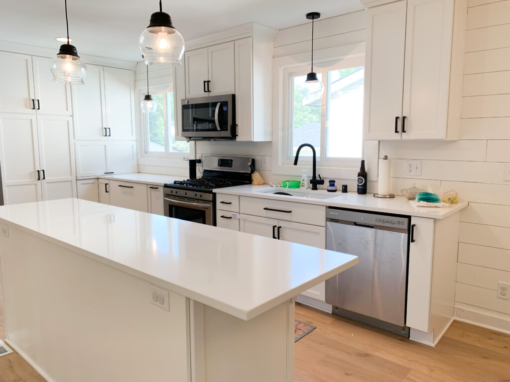 Modern white kitchen with island and appliances.