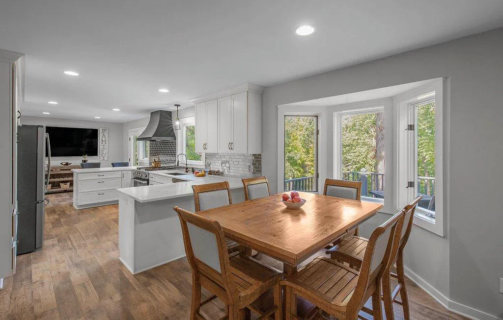 Open concept kitchen with white shaker cabinets, quartz island, stainless appliances, and adjacent dining area