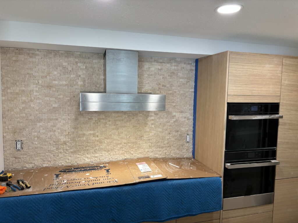 Modern kitchen with a sleek stove and blue cushioned bench.