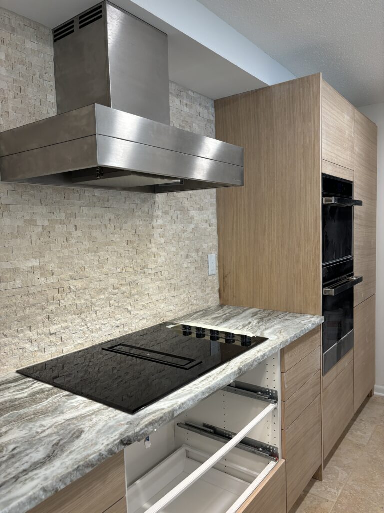 Modern kitchen with sleek stovetop and wooden cabinetry.